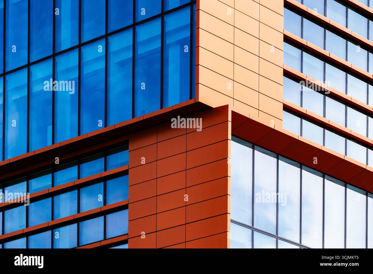 Moderno edificio per uffici con facciata geometrica in vetro caratterizzato da finestre aperte, forte simmetria e dettagli riflettenti del cielo. Foto Stock