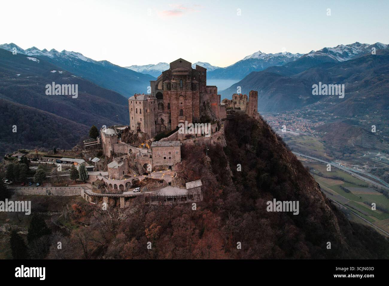 Vista aerea della Sacra di San Michele, una meraviglia architettonica medievale arroccata sulla cima di una montagna, le sue antiche pietre bagnate dal soffice bagliore del crepuscolo, Sacra di San Michele, Piemonte, Italia. Foto Stock