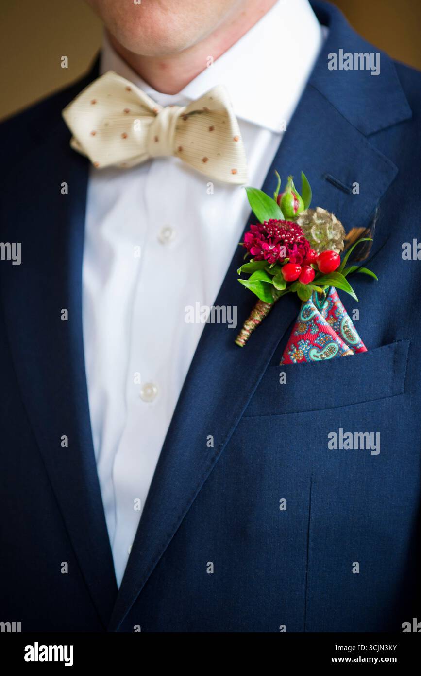 Sposo in tuta blu con cravatta e boutonnière floreale Foto Stock