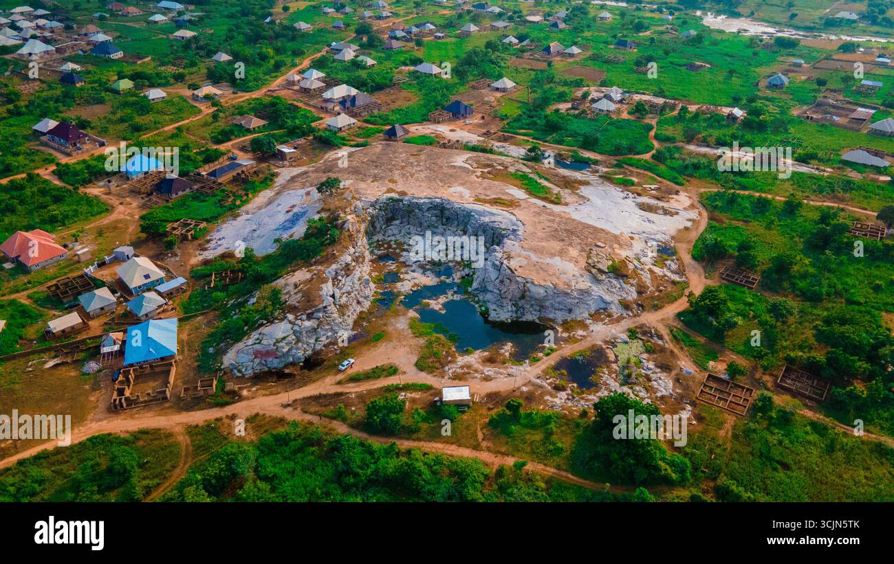 La vista aerea di un aspro paesaggio scavato rivela un netto contrasto tra la terra cruda e la vibrante vegetazione di Kwara, Kwara, Nigeria. Foto Stock