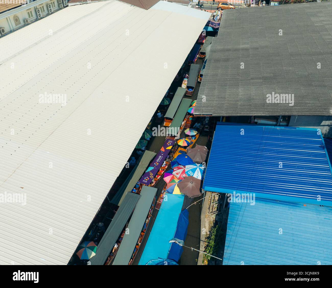 Vista aerea delle barche che navigano attraverso i vivaci corsi d'acqua, un vivace arazzo di ombrelli colorati e il tradizionale commercio tailandese, Damnoen Saduak, Thailandia. Foto Stock