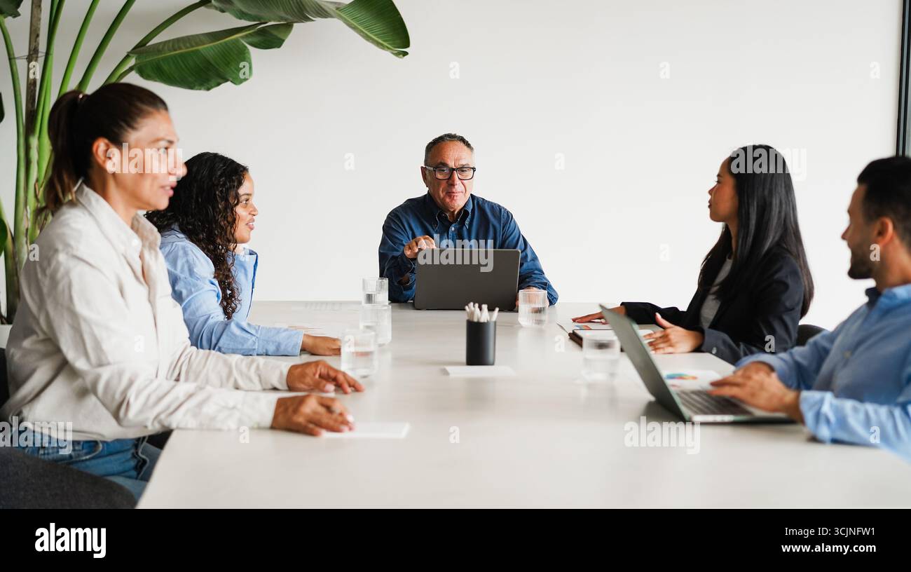 Uomini d'affari che condividono idee durante una riunione di lavoro di squadra all'interno di un ufficio minimale - colleghi multirazziali che discutono di un nuovo progetto finanziario - brainstorming Foto Stock