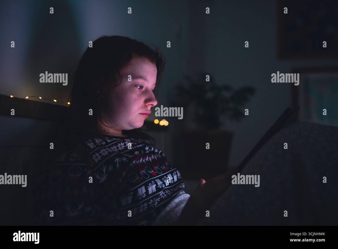 Ragazza adolescente che usa lo smartphone, tablet sdraiata a letto a tarda notte. Concetto di dipendenza dallo schermo per bambini. Foto Stock