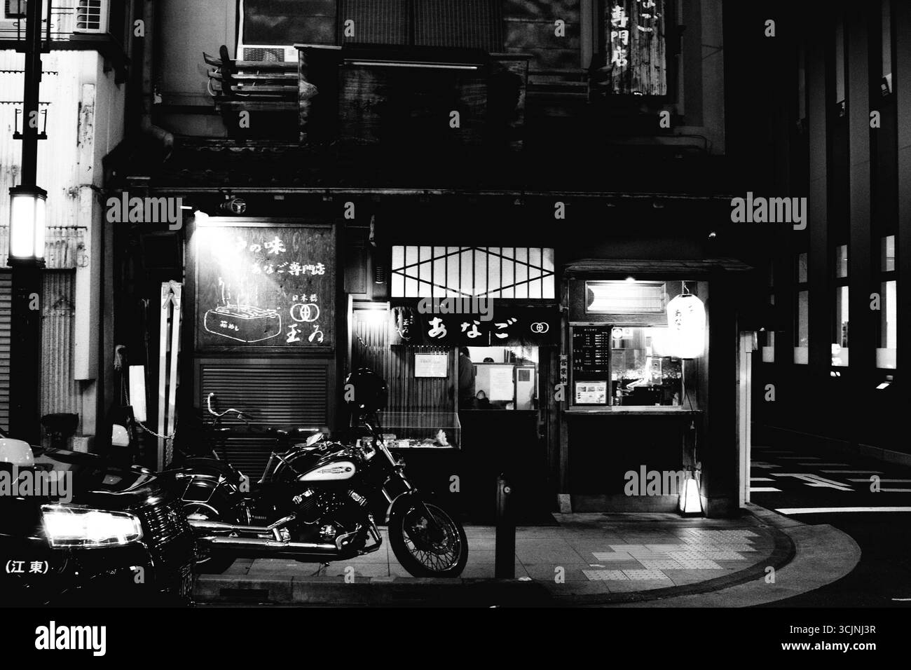 NIHONBASHI, TOKYO, GIAPPONE: Una foto cinematografica in bianco e nero di un ristorante tradizionale giapponese che si illumina di notte in una tranquilla strada secondaria. Atmosferico. Foto Stock