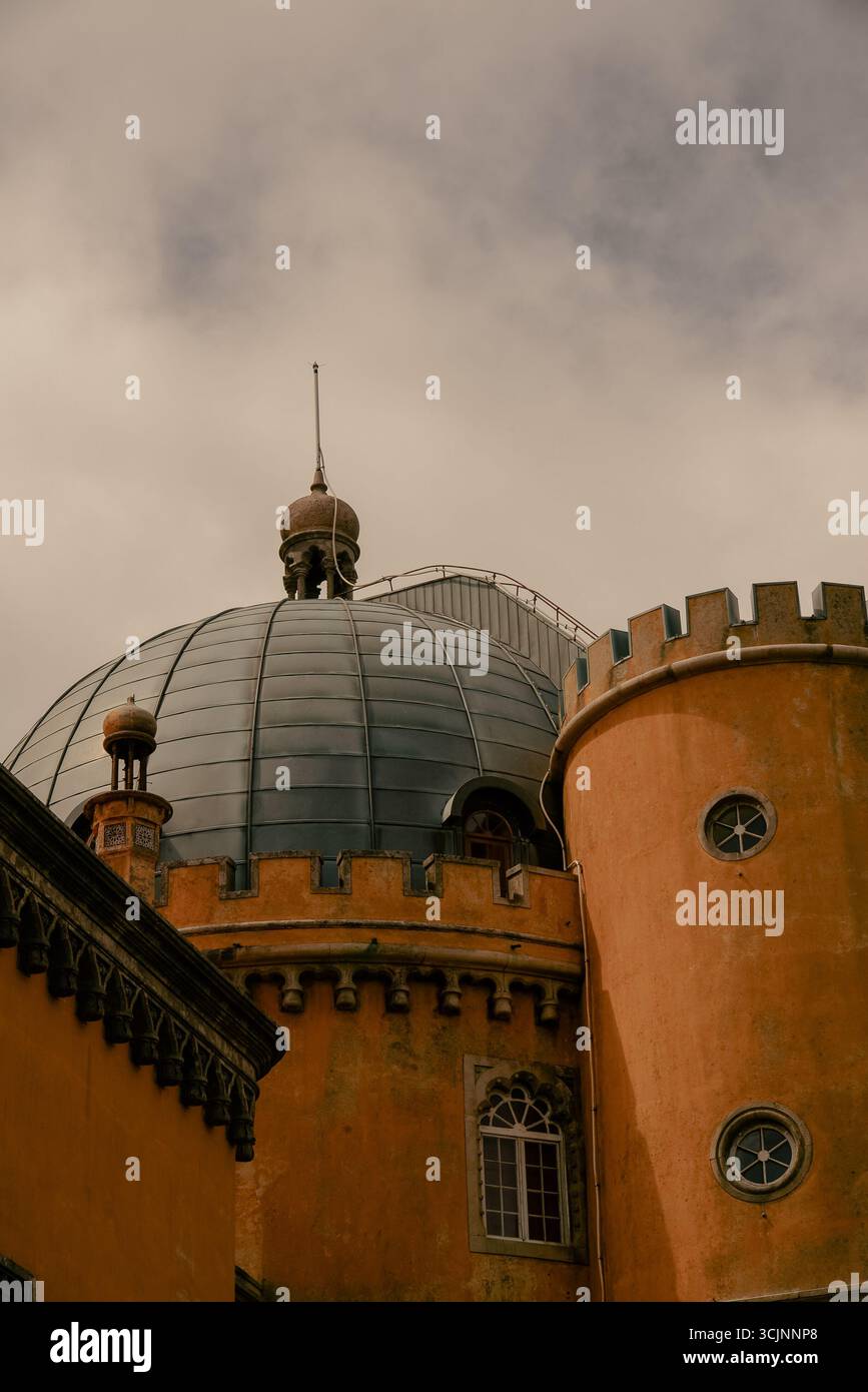 Dettaglio architettonico di un tetto a cupola in cima a una torre cilindrica gialla al Palácio da pena a Sintra, Portogallo. La struttura presenta un caratteristico castello-l Foto Stock