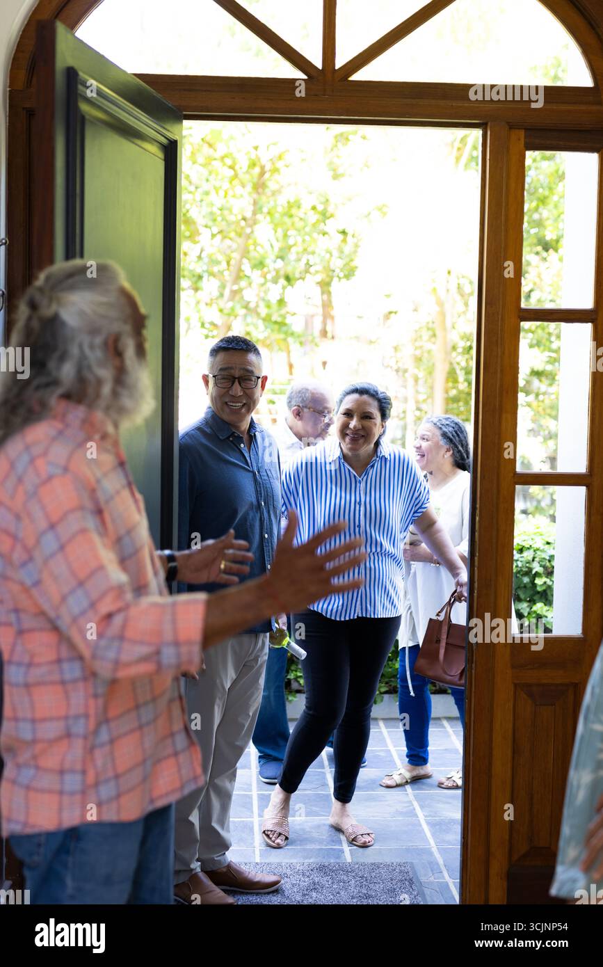 Accoglienza di amici, gruppi di anziani diversi che hanno una conversazione allegra a casa Foto Stock