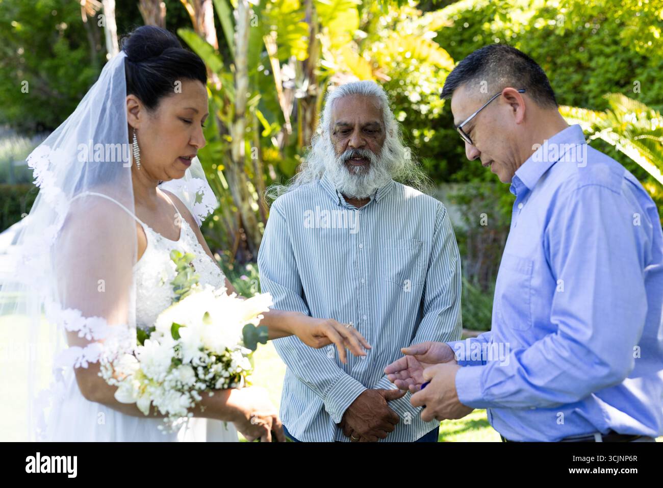 Scambiarsi anelli, sposo e sposo con l'officiante durante la cerimonia di nozze all'aperto Foto Stock