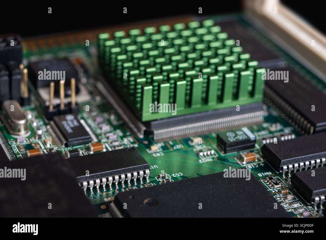 Primo piano di un'elegante scheda a circuito stampato con un dissipatore di calore verde, che mostra i componenti per l'intelligenza artificiale e la tecnologia delle criptovalute. Foto Stock