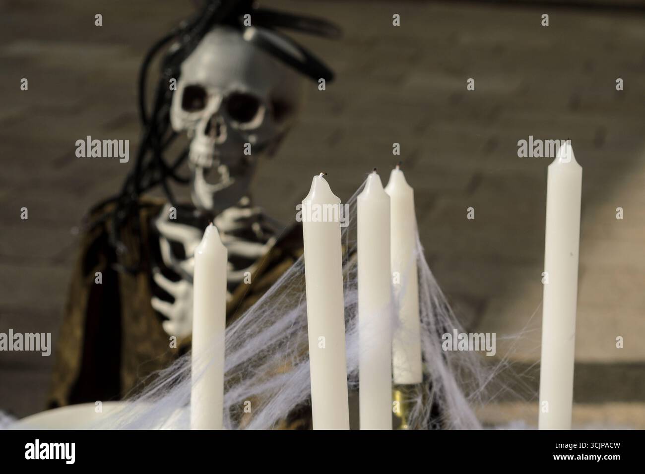 Focalizzazione selettiva sulle candele con uno scheletro raccapricciante che si infila dietro Foto Stock