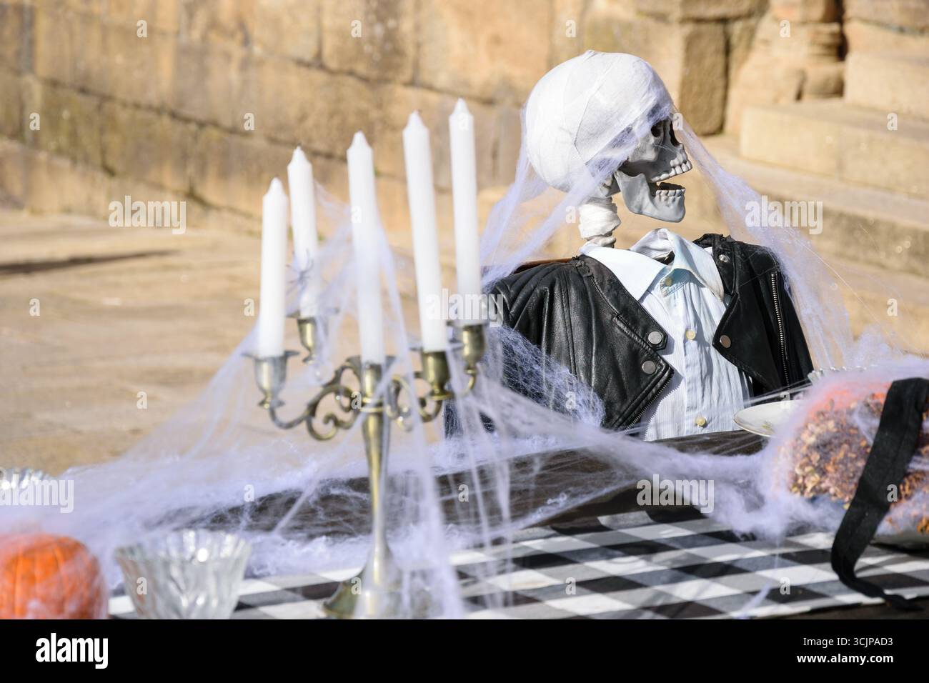 Divertente scena di Halloween di un ospite scheletro a una cena, Foto Stock
