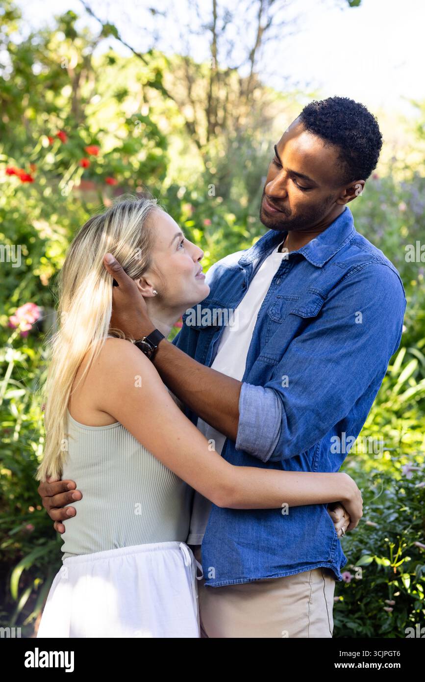 Coppia che abbraccia il giardino, sorride e godersi momenti romantici insieme Foto Stock