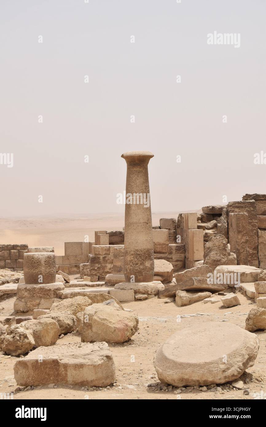 L'antico pilastro di pietra e le rovine dell'altopiano di Giza, il Cairo, in Egitto, mostrando blocchi intemprati e lo sfondo del deserto da un sito archeologico. Foto Stock