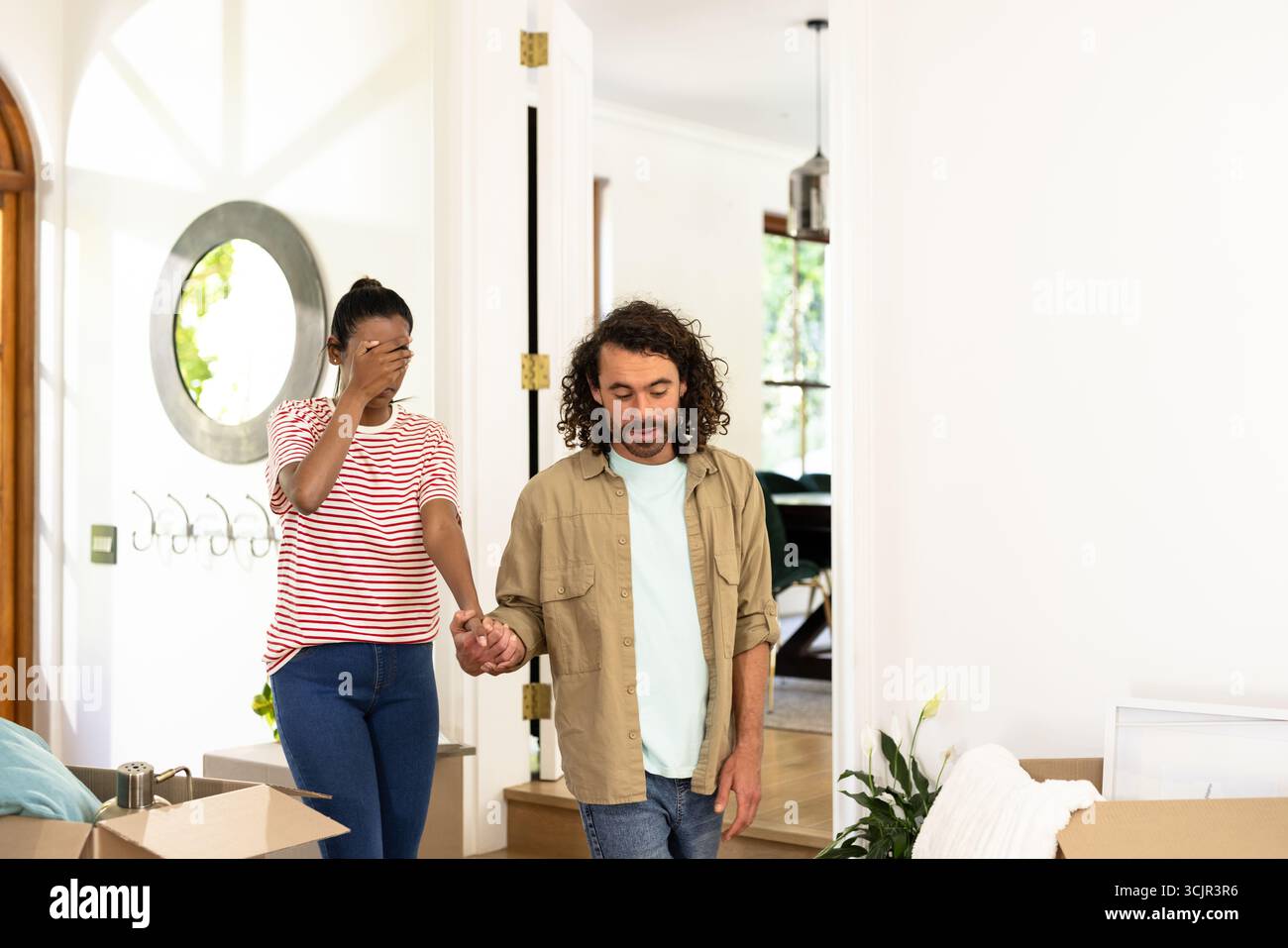 Coppia giovane e variegata che si tiene per mano, esplora una nuova casa, si sente emozionata ed emotiva Foto Stock