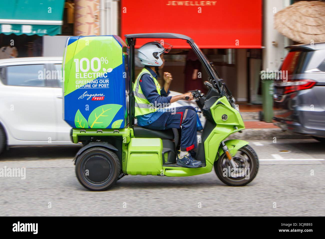 Addetto alla consegna su un triciclo elettrico verde in un ambiente urbano con consegna dell'ultimo miglio ecocompatibile singapore post SingPost Foto Stock