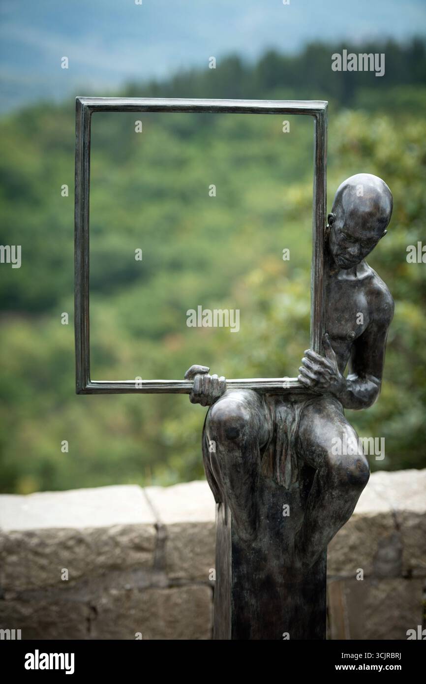 MONTEFIORALLE, ITALIA - 24 agosto 2025 - "l'uomo nello specchio" - scultura in bronzo di Boris Stampfli raffigura una figura umana che regge una cornice. Foto Stock