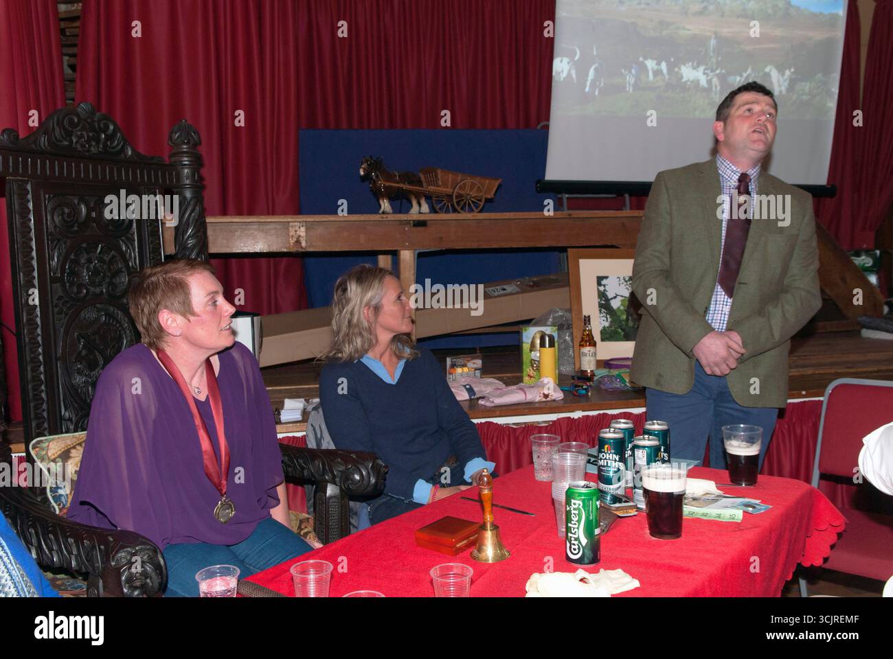 Linda Maloney (sindaco 2018-2019) siede alla presidenza dei sindaci durante la cerimonia annuale del Coniston Foxhounds Mayor Making Ceremony nell'Istituto Troutbeck (sala del villaggio). Indossa le insegne del sindaco di Troutbeck su un nastro rosso intorno al collo. La signora Helen Westmoreland-Nicholson, sindaco degli anni precedenti, siede al suo fianco. Dopo il Troutbeck Mayors Hunt Supper, un membro della comunità di caccia canta tradizionali canti di caccia della Cumbria. Troutbeck, Cumbria, Inghilterra 23 febbraio 2018 UK 2010s HOMER SYKES Foto Stock