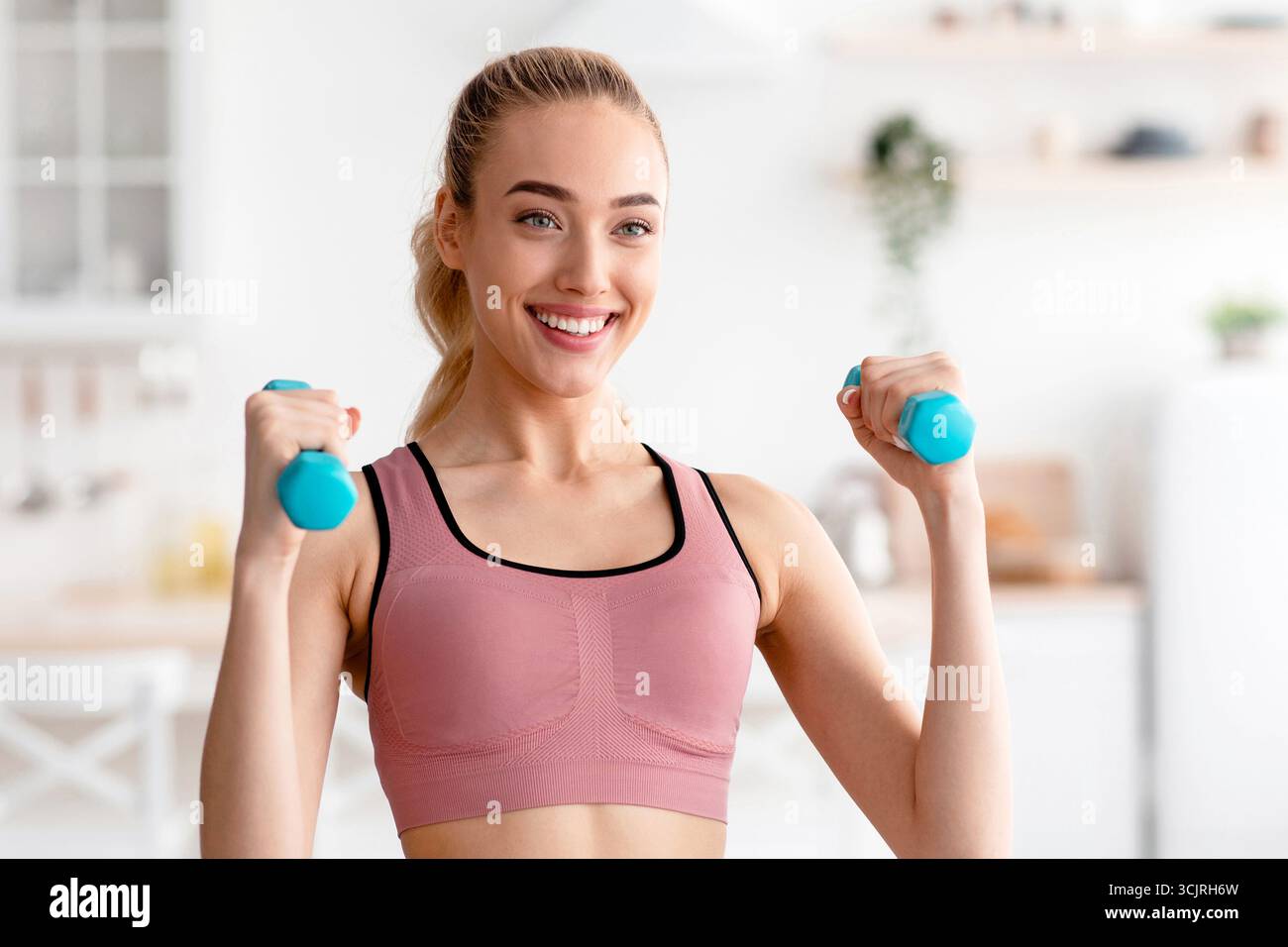 L'atleta felice lavora a casa, si esercita per le mani e si tiene in forma durante il blocco COVID-19 Foto Stock
