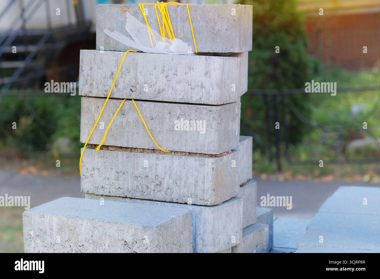 Blocchi grigi per la carreggiata. Pietre per pavimentazione marciapiede impilate. Testurizzati e pronti per la costruzione. Materiale da costruzione. Costruzione di edifici. Foto Stock