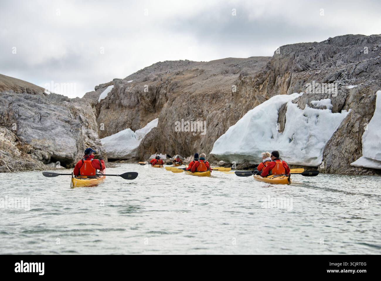 I kayak pagaiano attraverso il Murchisonfjord Nordaustlandet Svalbard // NORDEAUSTLANDET, Svalbard: I kayak navigano attraverso il Murchisonfjorden, un fiordo caratterizzato dalle sue aspre scogliere rocciose e dalle macchie di neve e ghiaccio. L'immagine cattura un gruppo di individui in kayak gialli, pagaiando attraverso le acque calme. Il Murchisonfjorden si trova su Nordaustlandet, la seconda isola più grande dell'arcipelago delle Svalbard. Le Svalbard sono un territorio artico amministrato dalla Norvegia, noto per i suoi ghiacciai, gli orsi polari e i paesaggi spettacolari. L'arcipelago si trova tra la Norvegia continentale e il po settentrionale Foto Stock I kayak pagaiano attraverso il Murchisonfjord Nordaustlandet Svalbard // NORDEAUSTLANDET, Svalbard: I kayak navigano attraverso il Murchisonfjorden, un fiordo caratterizzato dalle sue aspre scogliere rocciose e dalle macchie di neve e ghiaccio. L'immagine cattura un gruppo di individui in kayak gialli, pagaiando attraverso le acque calme. Il Murchisonfjorden si trova su Nordaustlandet, la seconda isola più grande dell'arcipelago delle Svalbard. Le Svalbard sono un territorio artico amministrato dalla Norvegia, noto per i suoi ghiacciai, gli orsi polari e i paesaggi spettacolari. L'arcipelago si trova tra la Norvegia continentale e il po settentrionale Foto Stock