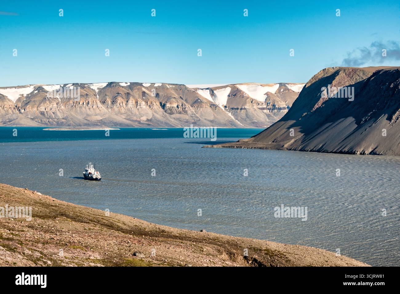 Nave da spedizione Polar Pioneer a Faksevagen Svalbard // SPITSBERGEN, SVALBARD — la nave da spedizione Polar Pioneer, gestita da Aurora Expeditions, naviga nelle acque vicino a Faksevågen nelle Svalbard. L'imbarcazione è vista sullo sfondo di aspre montagne innevate e un cielo azzurro. Le Svalbard, un arcipelago situato nell'Oceano Artico, sono note per i suoi suggestivi paesaggi glaciali e la fauna selvatica unica. Il Polar Pioneer è progettato per l'esplorazione polare, offrendo viaggi in ambienti remoti e incontaminati. La località fa parte del territorio delle Svalbard e Jan Mayen, un archipel norvegese Foto Stock