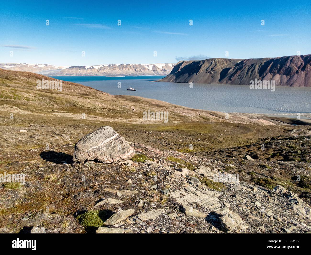 Nave da spedizione Polar Pioneer a Faksevagen Svalbard Norvegia // SVALBARD, NORVEGIA — la nave da spedizione Polar Pioneer, gestita da Aurora Expeditions, naviga in un fiordo vicino a Faksevågen, Svalbard. La nave è vista su uno sfondo di terreno montuoso, con ghiacciai visibili sulle vette lontane. Il paesaggio presenta aspre pendici rocciose ricoperte da una vegetazione sparsa, caratteristica dell'ambiente artico. Questa regione delle Svalbard è conosciuta per i suoi suggestivi fiordi, ghiacciai e la fauna selvatica unica, attirando spedizioni polari e appassionati della natura. Polar Pioneer è progettato per navigare su ghiaccio Foto Stock