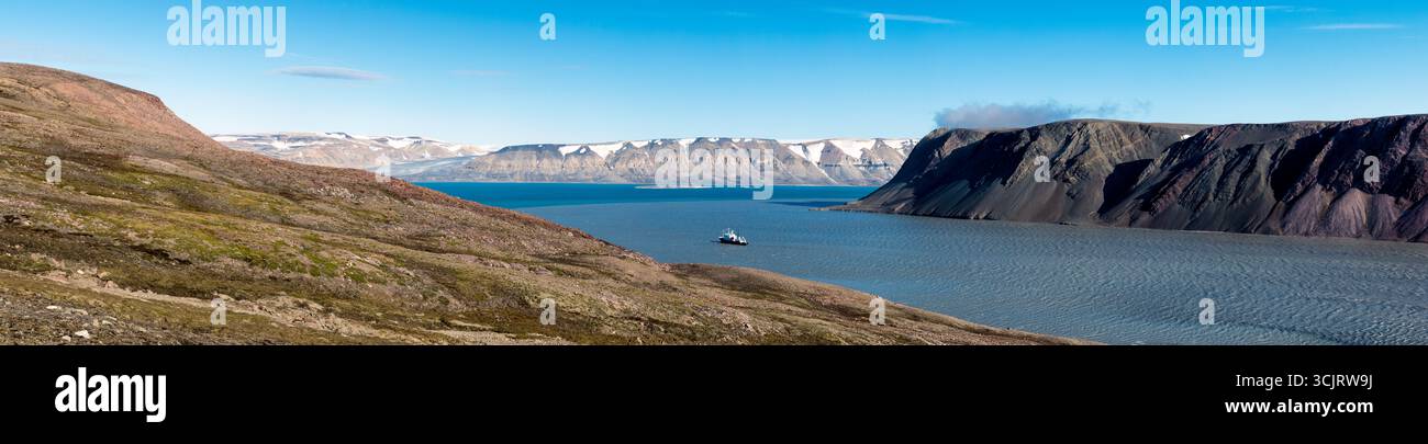 Nave da spedizione Polar Pioneer Faksevagen Svalbard Norvegia // FAKSEVÅGEN, Svalbard, Norvegia — la nave da spedizione Polar Pioneer, gestita da Aurora Expeditions, naviga nelle acque di Faksevågen nelle Svalbard. La nave è vista su uno sfondo di aspre montagne scarsamente vegetate e una catena montuosa lontana innevata sotto un cielo azzurro. Faksevågen è una baia situata sulla costa occidentale di Spitsbergen, la più grande isola dell'arcipelago delle Svalbard. Le Svalbard sono un territorio artico conosciuto per i suoi paesaggi spettacolari, i ghiacciai e la fauna selvatica unica. Il Pioneer polare è progettato per l'ex polare Foto Stock