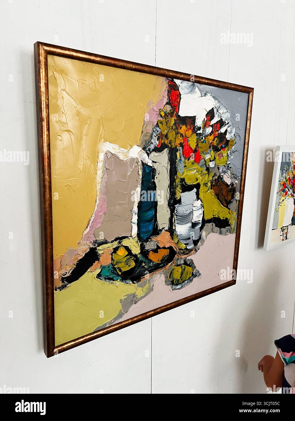 Tarnopil, Ucraina - 10 agosto 2025: Opere d'arte astratte moderne con pennellate vivaci e tonalità calde, incorniciate in oro. Foto Stock