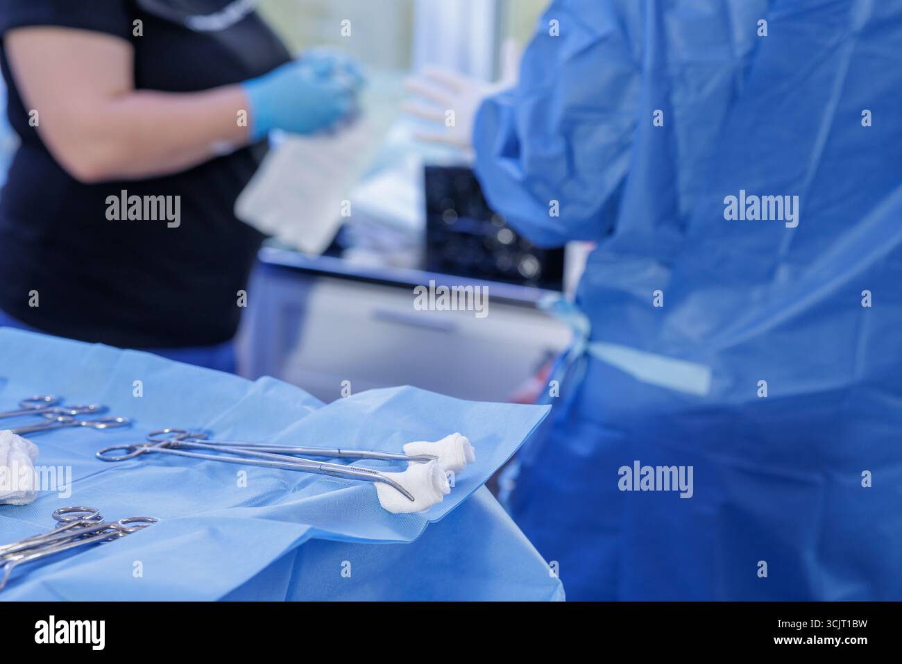 Campo sterile preparato con emostatici e garza, mentre il personale prepara una procedura in un ambiente clinico pulito Foto Stock