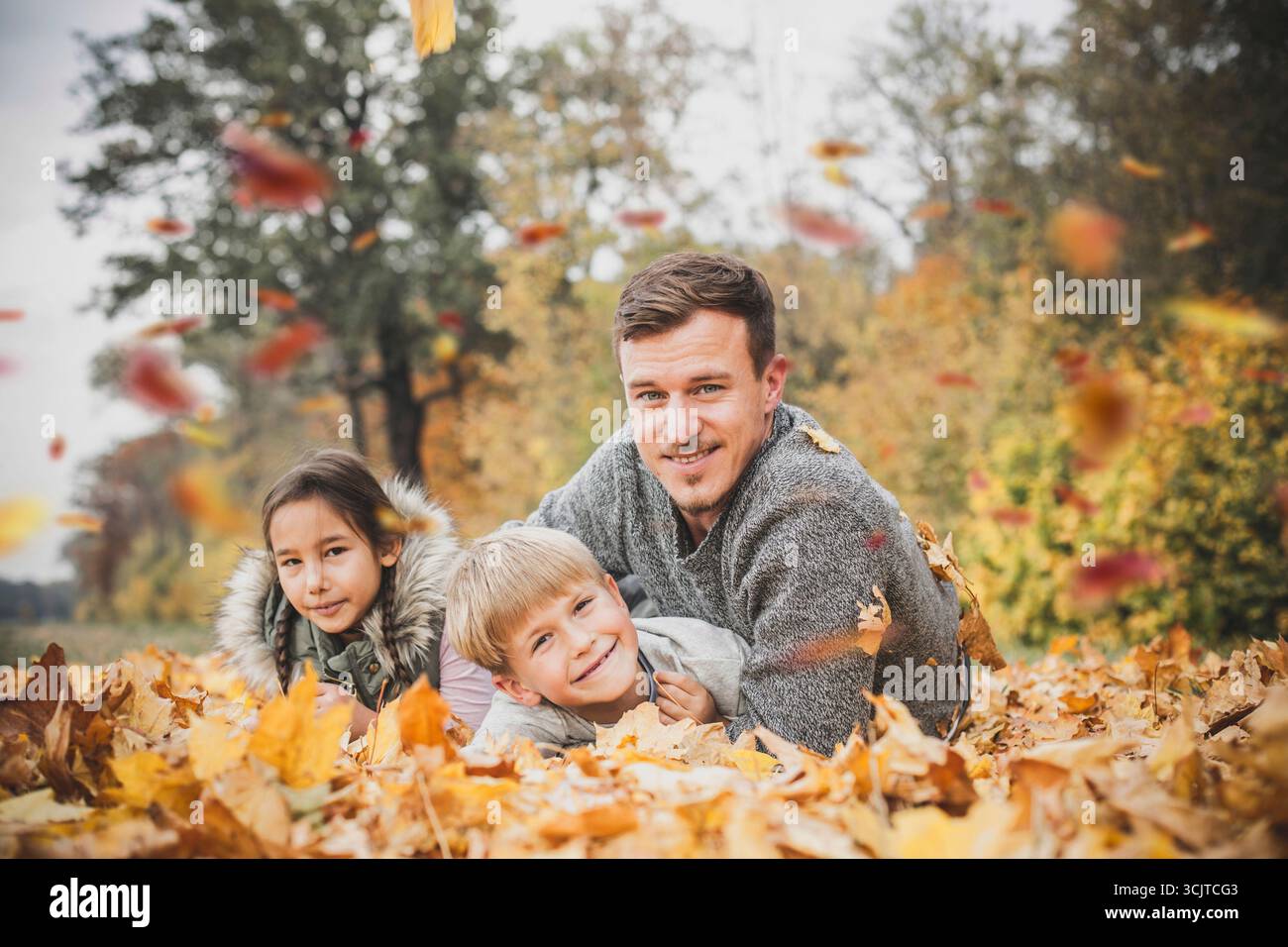padre che si prende in giro in autunno parte con i suoi figli Foto Stock