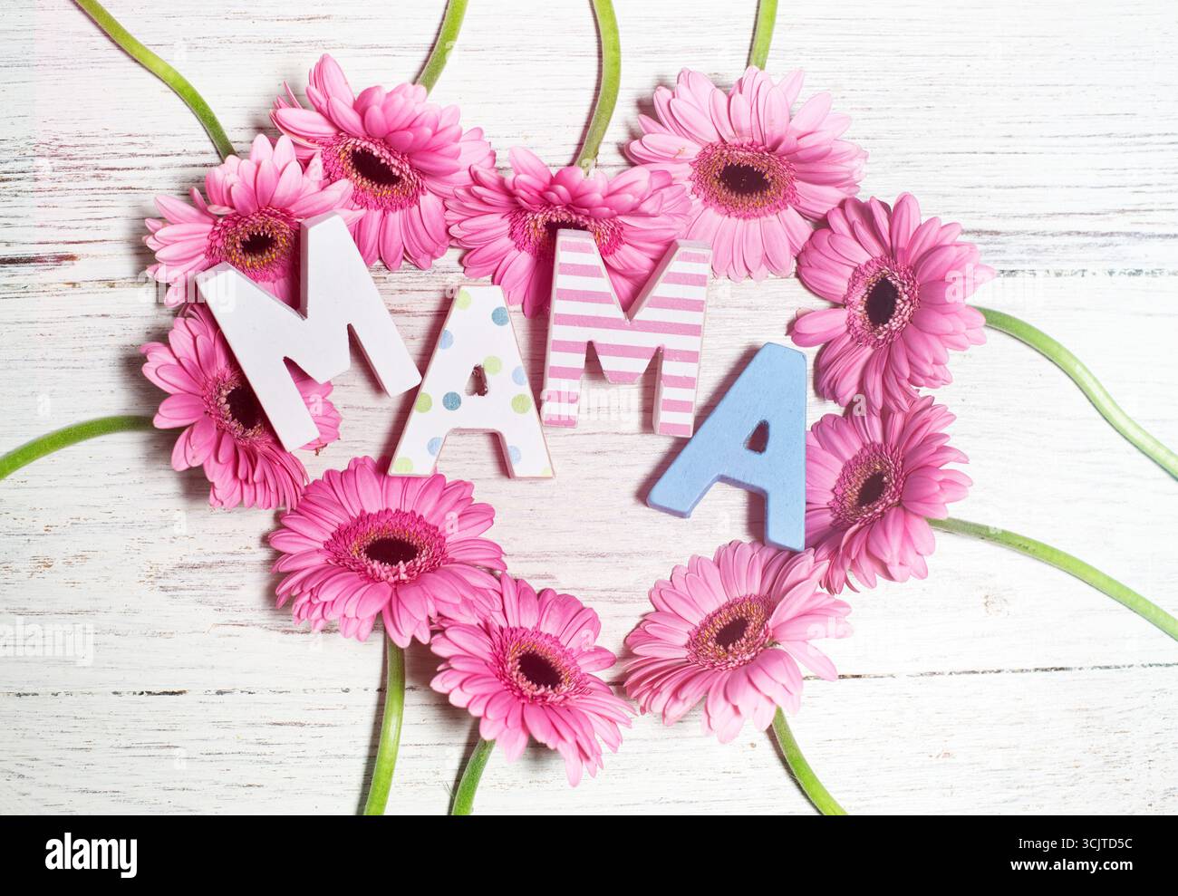 La parola tedesca mamma, mamma, su un cuore di gerberas rosa come saluto per la festa della mamma Foto Stock