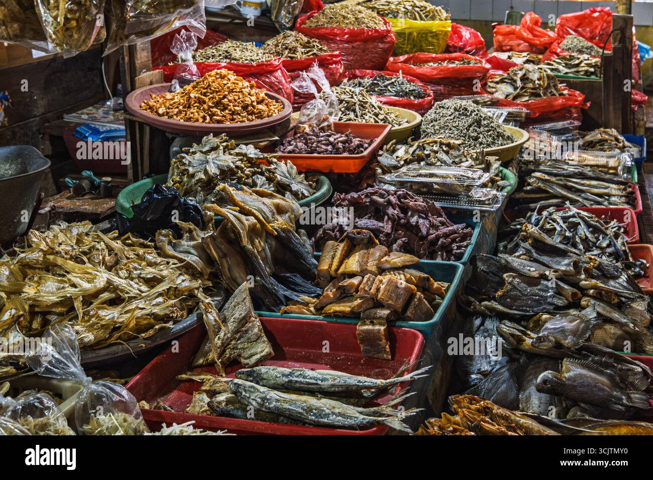 Balikpapan, Indonesia - 22 agosto 2025. Vari tipi di pesce secco e prodotti a base di pesce esposti in vassoi e sacchi in un mercato tradizionale. Foto Stock