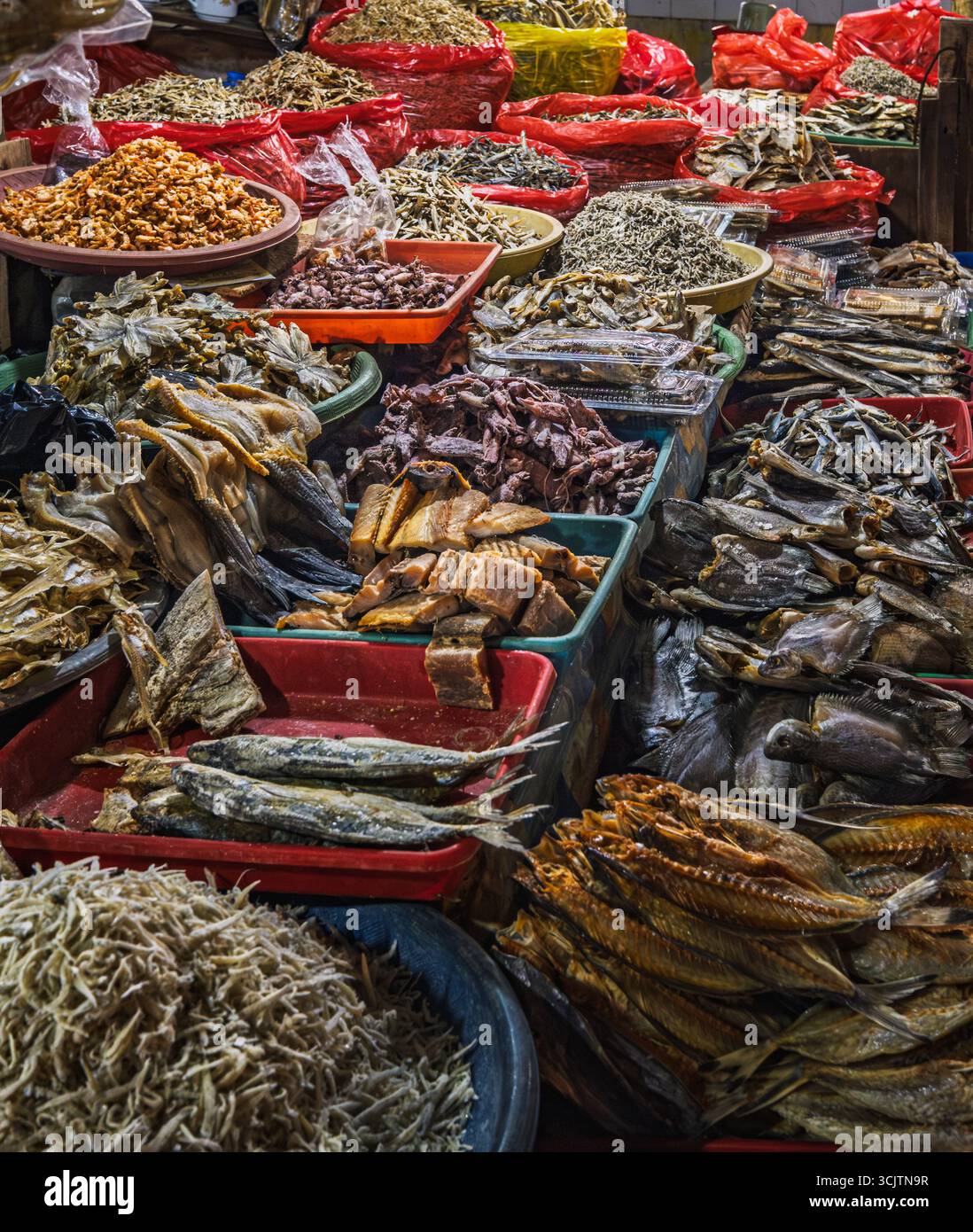 Balikpapan, Indonesia - 22 agosto 2025. Pesci secchi assortiti, acciughe e prodotti a base di pesce esposti in cesti e vassoi in una tradizionale Indonesia Foto Stock