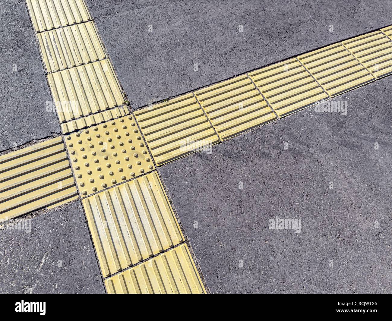 dettagli della pavimentazione pedonale. indicatori gialli antiscivolo tattili sul marciapiede della città. Foto Stock