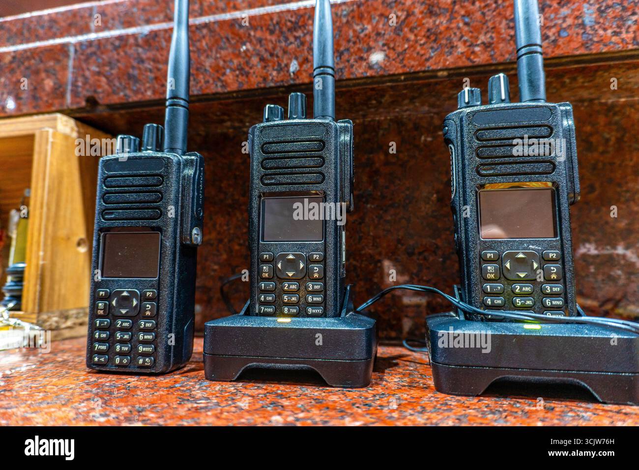 Tre walkie-talkie sono posizionati sulle basi di ricarica con spie accese, pronte per la comunicazione e l'uso della risposta di emergenza. Foto Stock