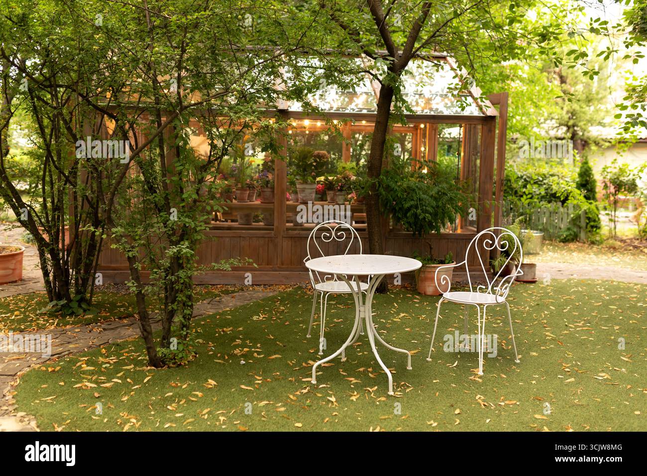 tavolo e sedie in giardino per rilassarsi. Cortile con set di mobili da giardino. Accogliente patio interno di casa. Foto Stock