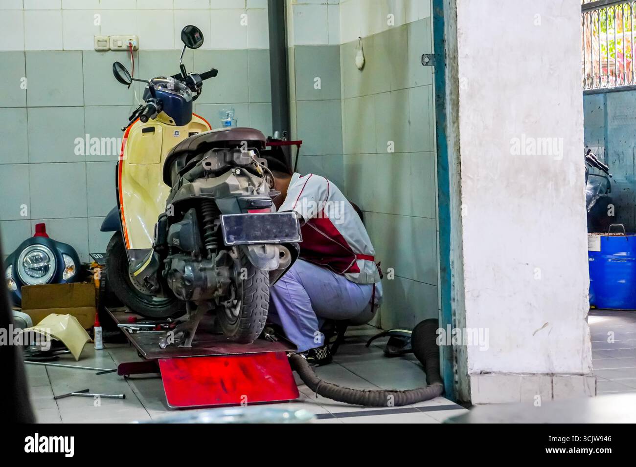 Un tecnico ripara il motore di una motocicletta in un garage utilizzando un ascensore, garantendo prestazioni e manutenzione ottimali questa immagine è ideale per il settore automobilistico o. Foto Stock