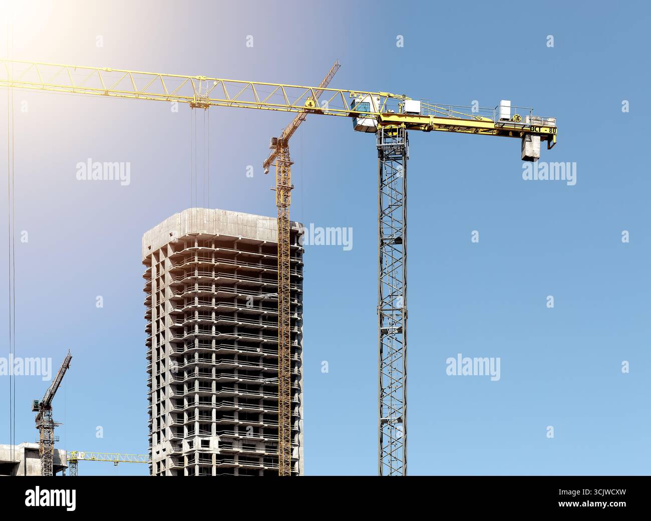 Costruzione di un alto edificio residenziale con struttura in blocchi di cemento, casseforme in acciaio, gru e macchinari gialli. Imprenditori immobiliari urbani Foto Stock