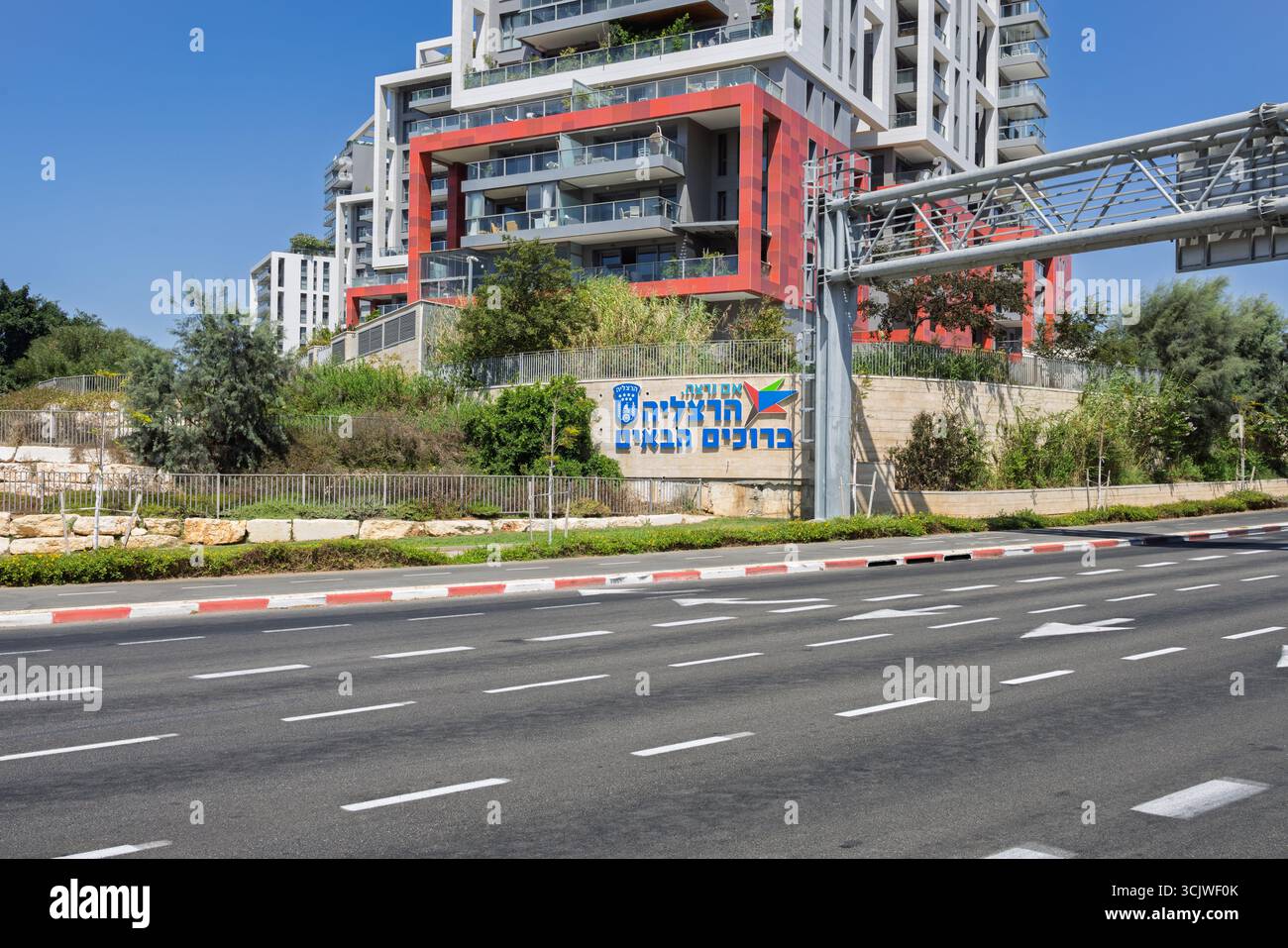 Herzliya, Israele. 6 settembre 2025. Cartello di benvenuto all'ingresso della città, un'autostrada di fronte e edifici moderni sullo sfondo. Testo ebraico: "IM Foto Stock