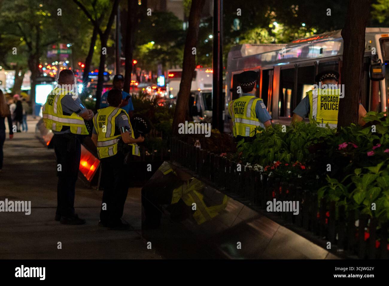 Gli agenti di polizia pattugliano una tranquilla strada urbana di notte, simboleggiando l'autorità, la sicurezza pubblica e l'impegno per la protezione della comunità dopo il tramonto. Foto Stock