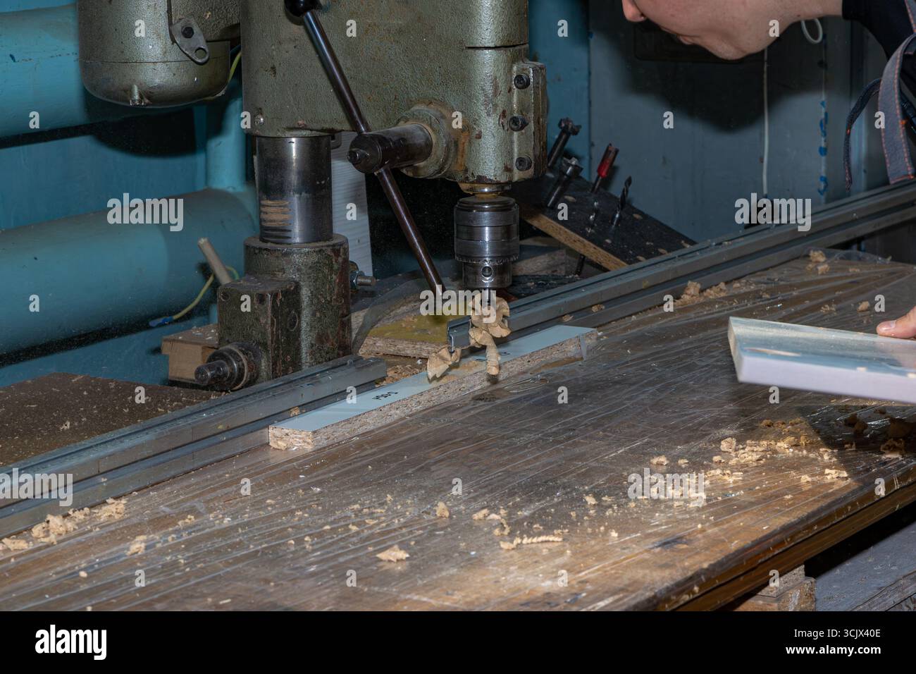 Una vecchia e robusta pressa da perforazione della metà del XX secolo, che mostra segni di lungo utilizzo con ruggine e trucioli di legno intorno ad essa. con attenzione selettiva al modello di foratura Foto Stock