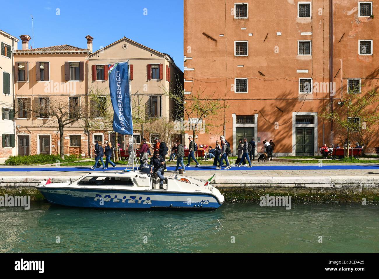 Una barca della polizia ormeggiata alla fondamenta de l'Arsenal, con una bandiera pubblicitaria della nave a vela Amerigo Vespucci, scalo a Venezia, Veneto, Italia Foto Stock