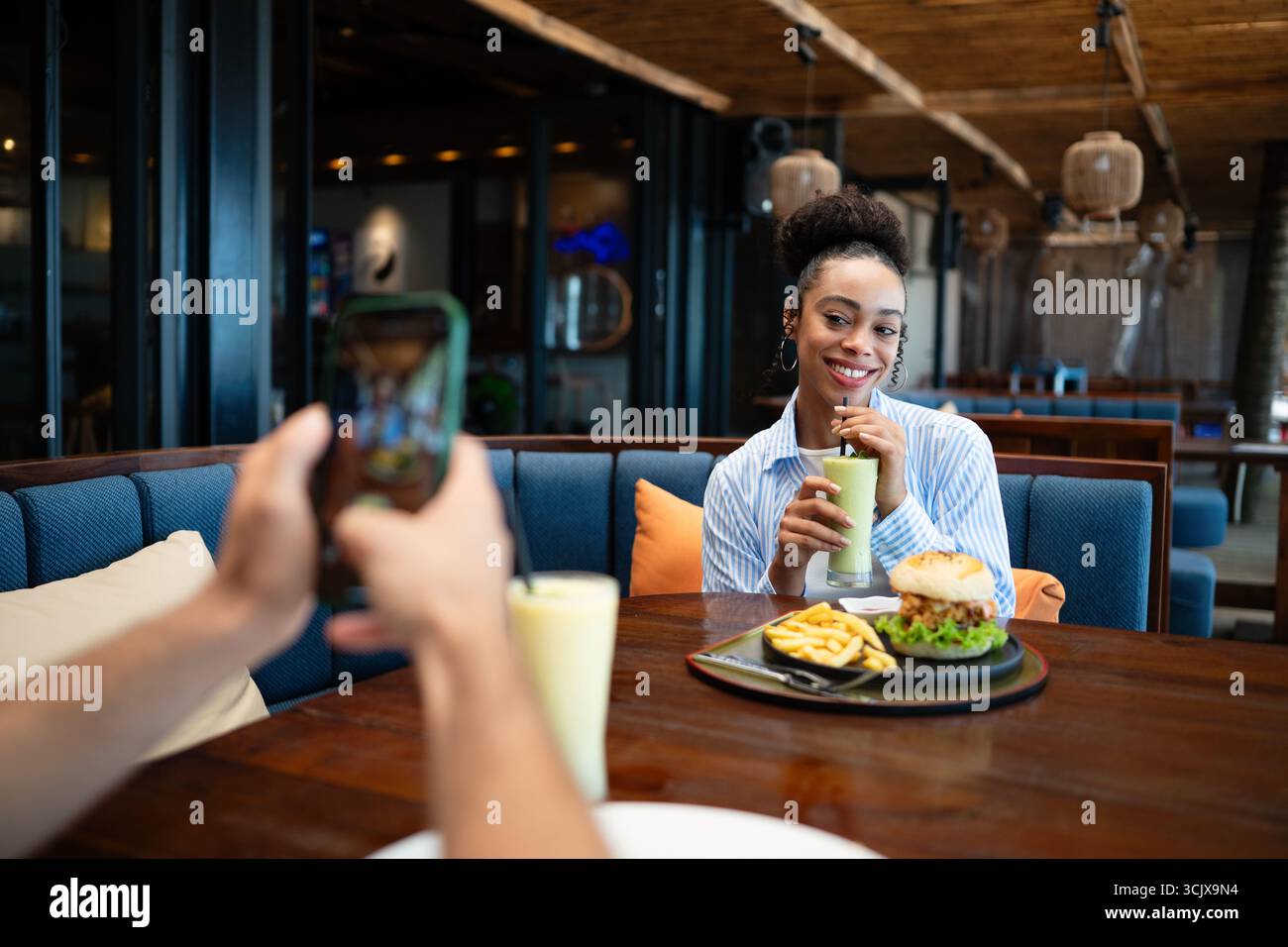 Coppie diverse in un appuntamento gastronomico si godono una cena informale e un momento al telefono, condividendo le vibrazioni soleggiate e le bevande Foto Stock