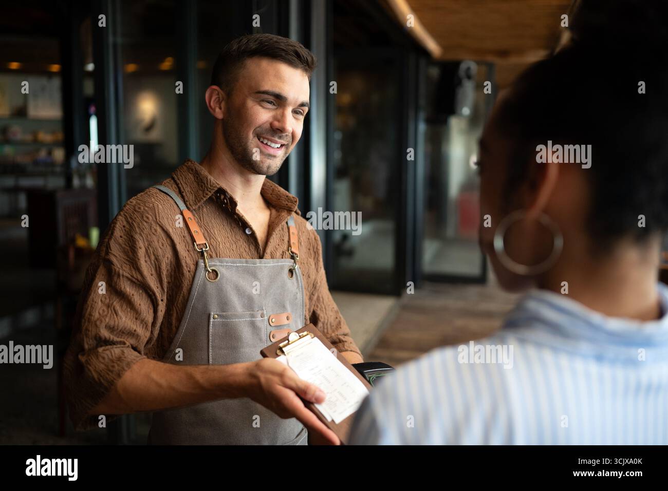 Barista appassionato e imprenditore che porta calore e servizio di qualità nella sua elegante caffetteria Foto Stock
