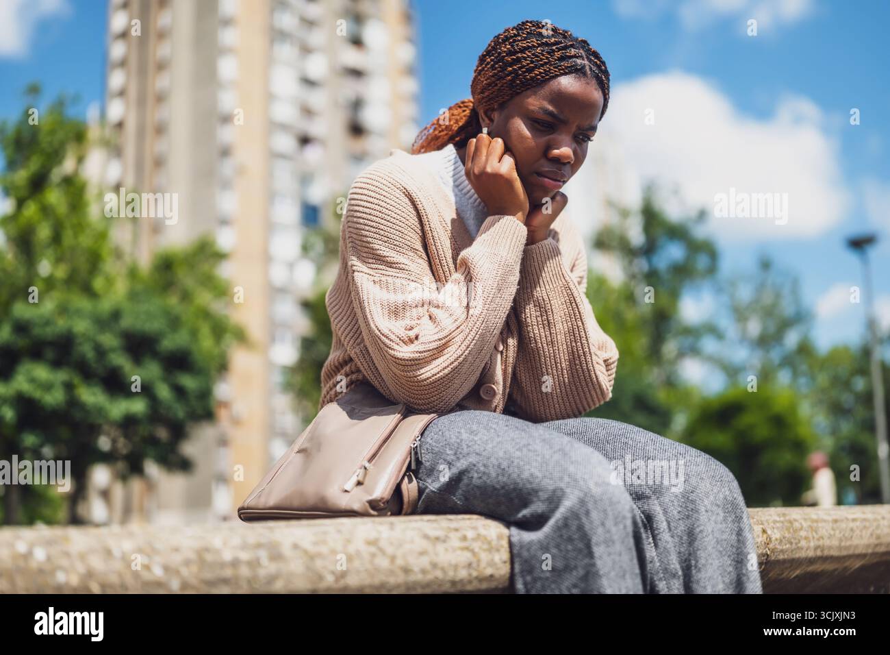 Ritratto dello stile di vita urbano di una donna afroamericana depressa che affronta lo stress emotivo, seduta nel parco cittadino. Foto Stock