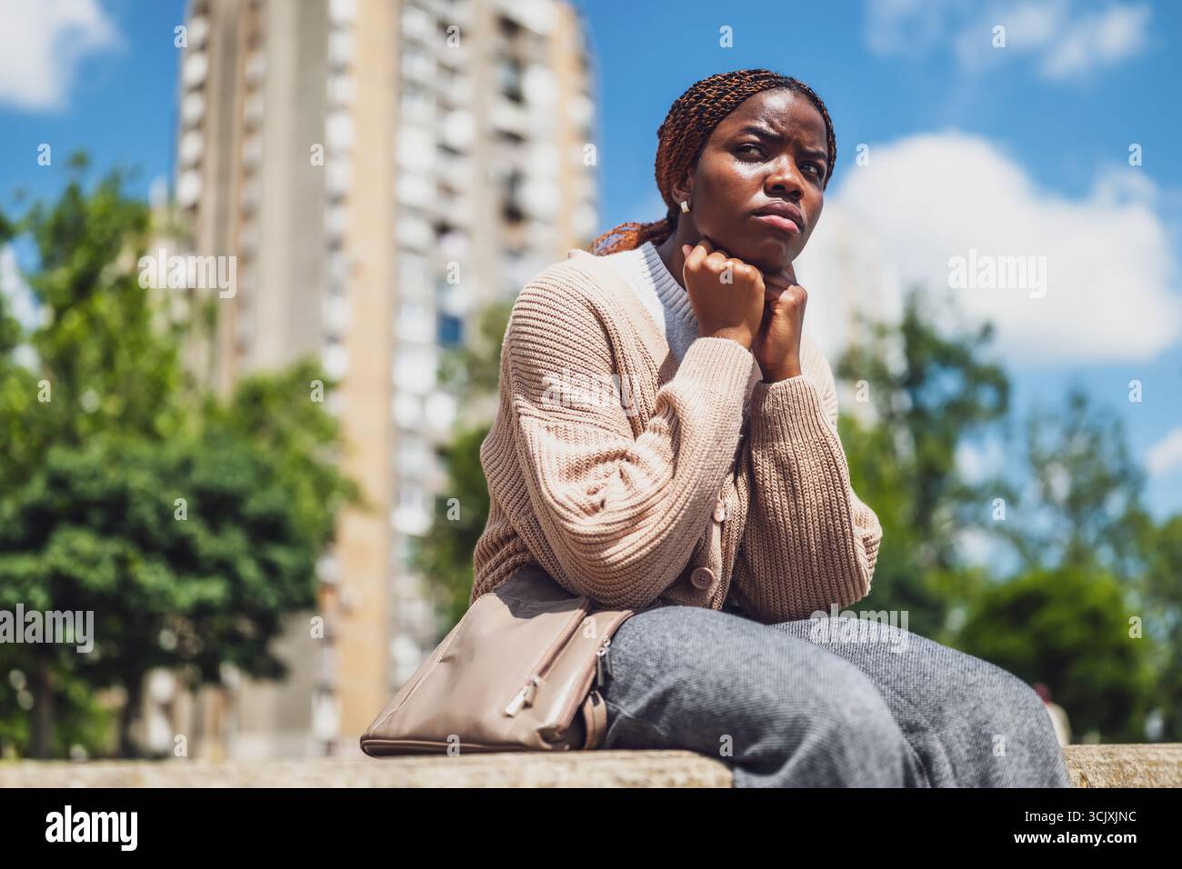 Ritratto dello stile di vita urbano di una donna afroamericana depressa che affronta lo stress emotivo, seduta nel parco cittadino. Foto Stock
