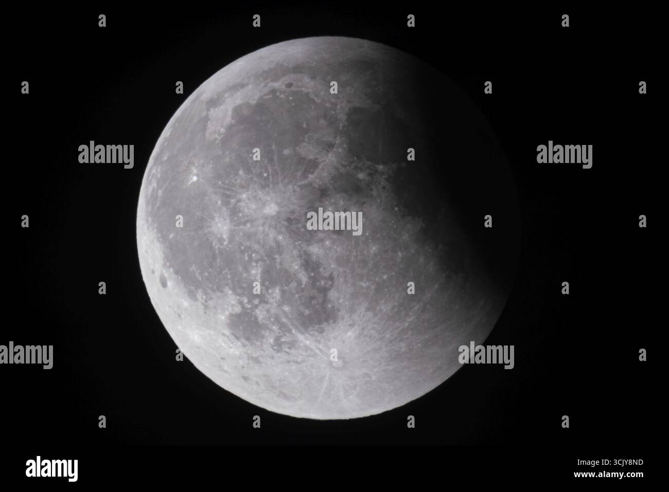 Dopo un'eclissi lunare totale, la luna appare poco dopo la sua ascesa nel cielo serale come una cosiddetta luna di sangue di fronte ad essa, quindi inizia ad emergere Foto Stock