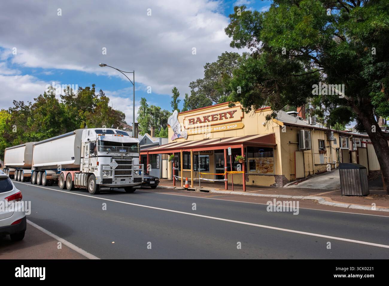 Un camion pesante e un rimorchio passeranno davanti alla Hansens Hot Bread Shop, una famosa panetteria a Bridgetown, una città di campagna nell'Australia Occidentale Foto Stock