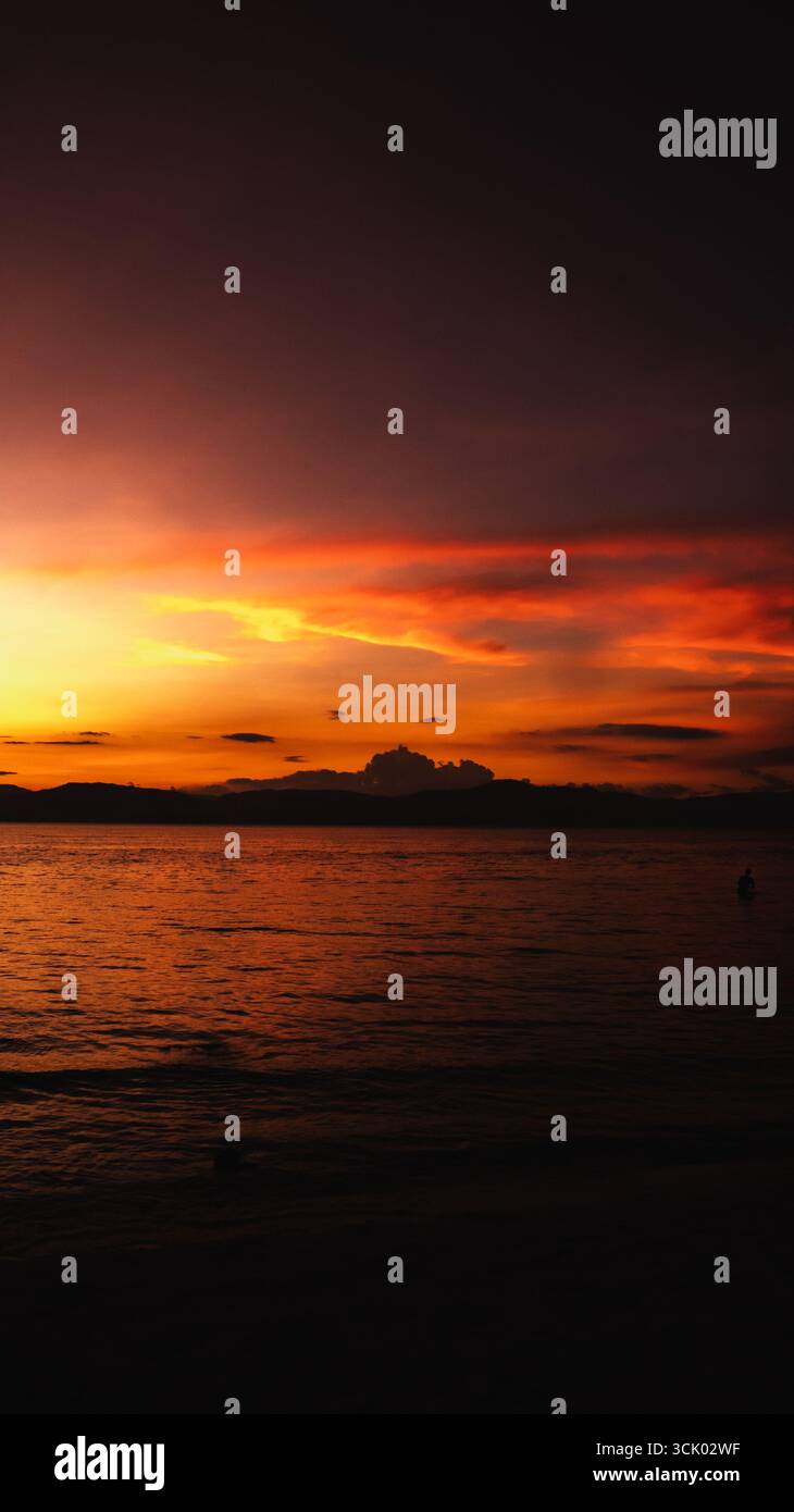 Splendido tramonto che crea una vista estetica in una combinazione di colori rosso, giallo, arancione e motivi che si affacciano sull'oceano, tranquillo e tranquillo Foto Stock