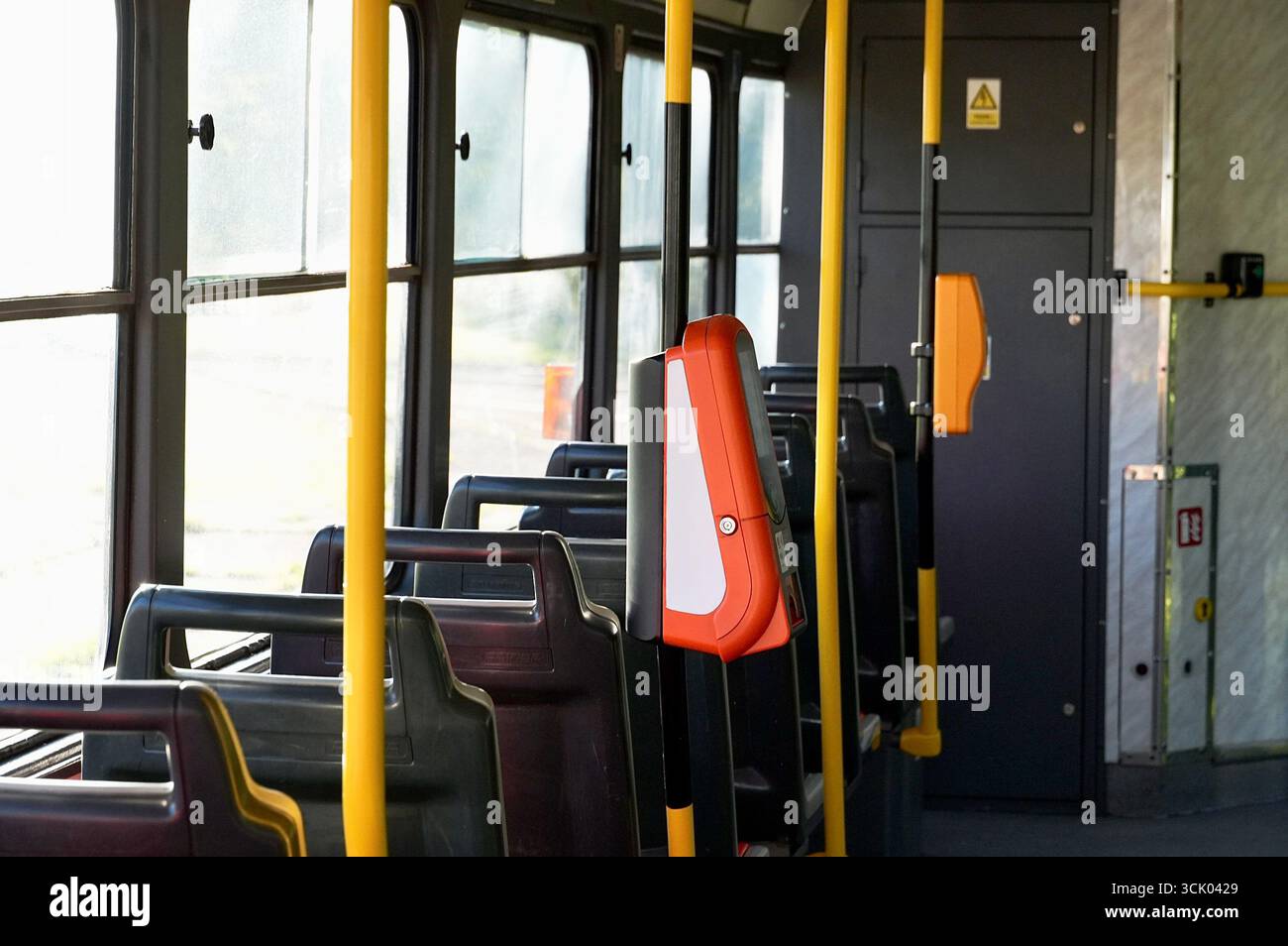 Interno di un autobus con posti a sedere gialli e neri e porta rossa Foto Stock