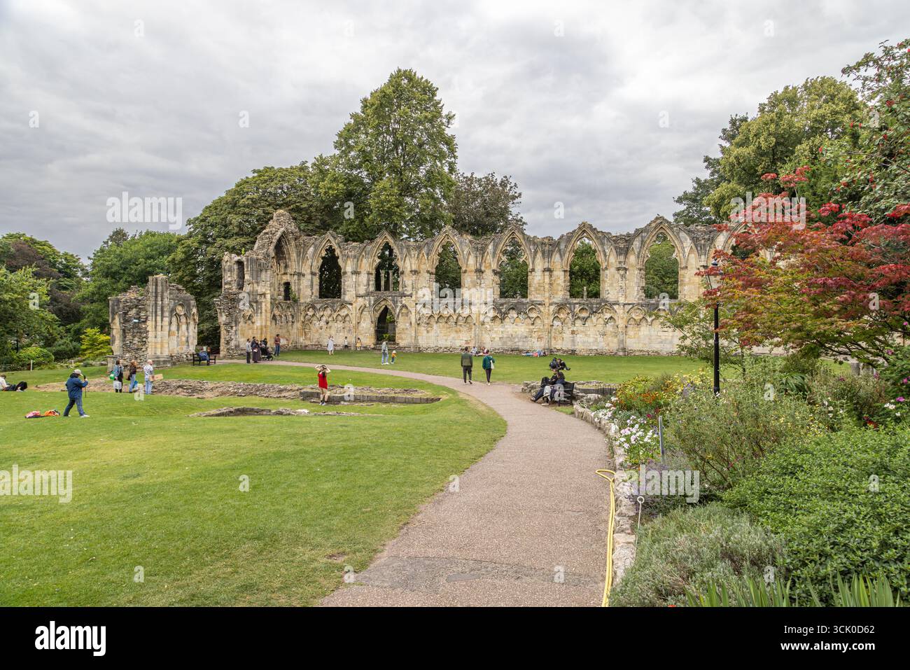 Rovine dell'abbazia di St Mary a York Museum Gardens, Inghilterra, con finestre ad arco gotico, muri in pietra intemprati, prati verdi e visitatori. Foto Stock